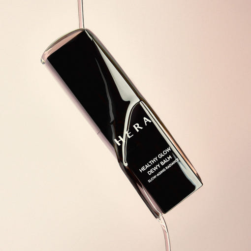 ProtoClinical k-beauty HERA HEALTHY GLOW DEWY BALM 10g dark diagonal balm silhouette on a warm beige background.