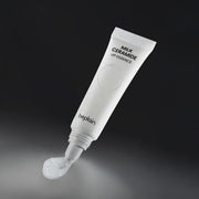 ProtoClinical k-beauty beplain Milk Ceramide Lip Essence 10g white squeeze tube angled above a glossy clear balm swatch on a dark charcoal background