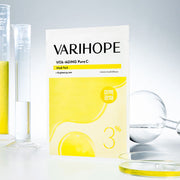 ProtoClinical k-beauty VARIHOPE: Vita-aging Pure C Mask Pack Ea (25ml x 5) bright yellow mask pack box standing upright over stacked boxes on a soft yellow background