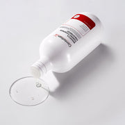 ProtoClinical k-beauty CENTELLIAN24 Toning Essence Treatment 300ml white treatment bottle lying on its side with a red label and clear liquid pooled on a white background