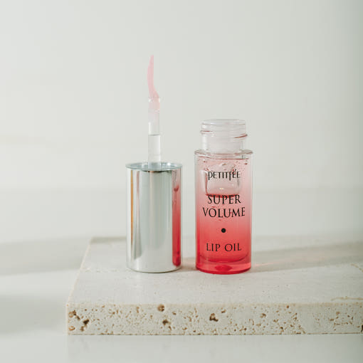 ProtoClinical k-beauty PETITFEE Super Volume Lip Oil 3g single taupe lip oil bottle standing upright on a pale aqua and cream background