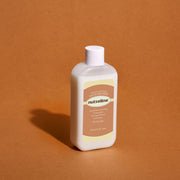 ProtoClinical k-beauty warm amber beauty product silhouette with a darker side accent on a brown background.