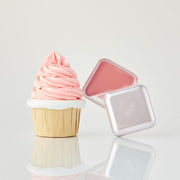 ProtoClinical k-beauty CLIO Essential Lipcheek Tap Blur 4.5g (4colors) open triangular pink balm compact beside a pink swirled cupcake on a pale background