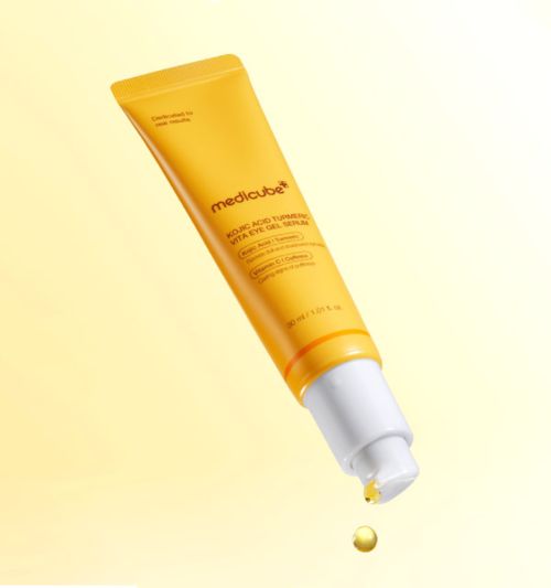 ProtoClinical k-beauty medicube Kojic Acid Turmeric Vita Eye Gel Serum 30ml yellow tube angled downward with one serum droplet falling from the white pump against a pale yellow background