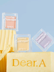 ProtoClinical k-beauty Dear.A Personal Single Concealer 1.8g (10colors) three clear square concealer compacts in peach, cream, and lavender shades arranged on yellow blocks against a pale blue background