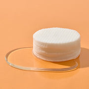 ProtoClinical k-beauty Hanskin Cleansing Pad & Blackhead 200ml/70ea stacked round textured cleansing pads resting on a clear gel puddle against a soft peach background