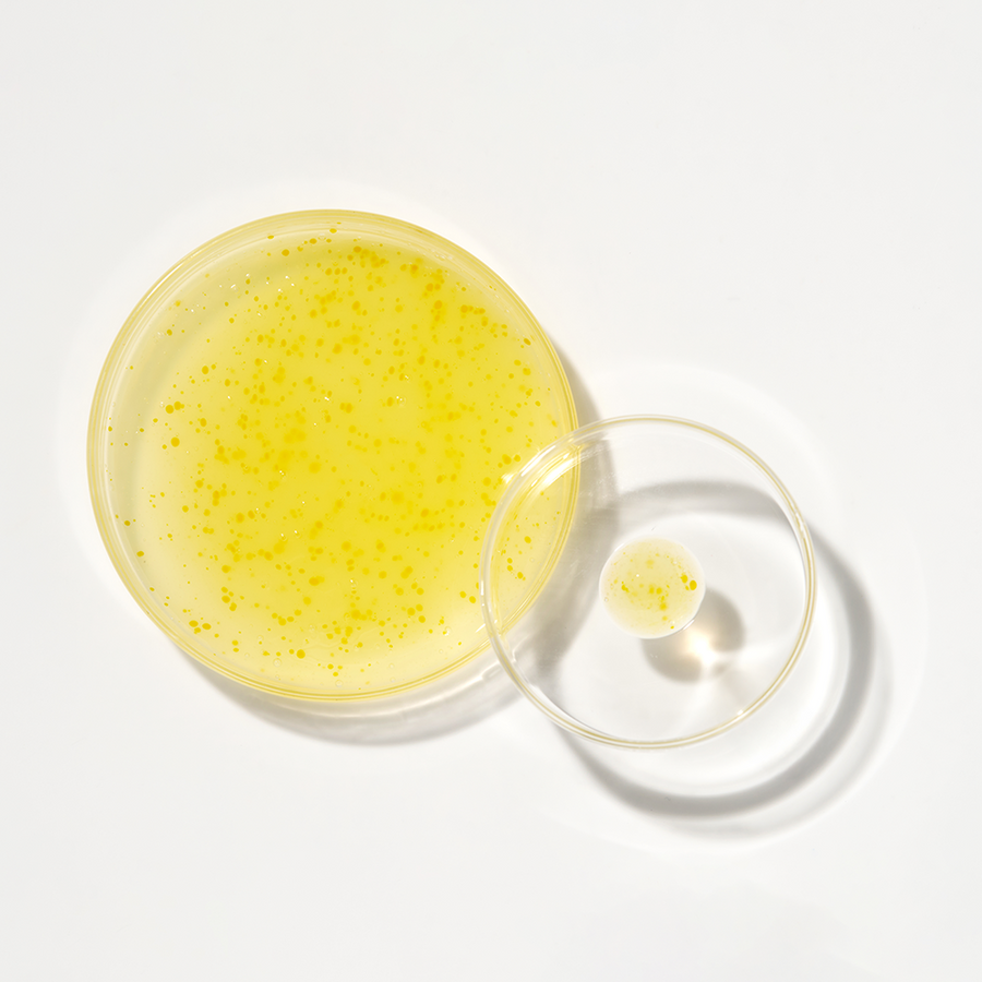 ProtoClinical k-beauty K-SECRET SEOUL 1988 GLOW SERUM : NIACINAMIDE 15% + YUJA 30ml as a single golden-yellow serum bottle centered on a pale blue and cream background