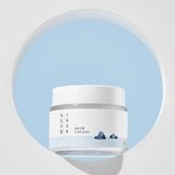 ProtoClinical k-beauty ROUND LAB 1025 DOKDO Cream 80mL abstract beauty graphic with pastel aqua, pink, and lavender diagonal bands on a pale background.