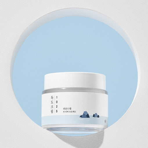 ProtoClinical k-beauty ROUND LAB 1025 DOKDO Cream 80mL abstract beauty graphic with pastel aqua, pink, and lavender diagonal bands on a pale background.